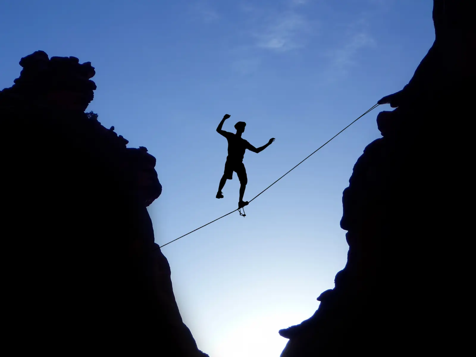 Silhouette of a tightrope walker between cliffs, representing margin of safety in investing